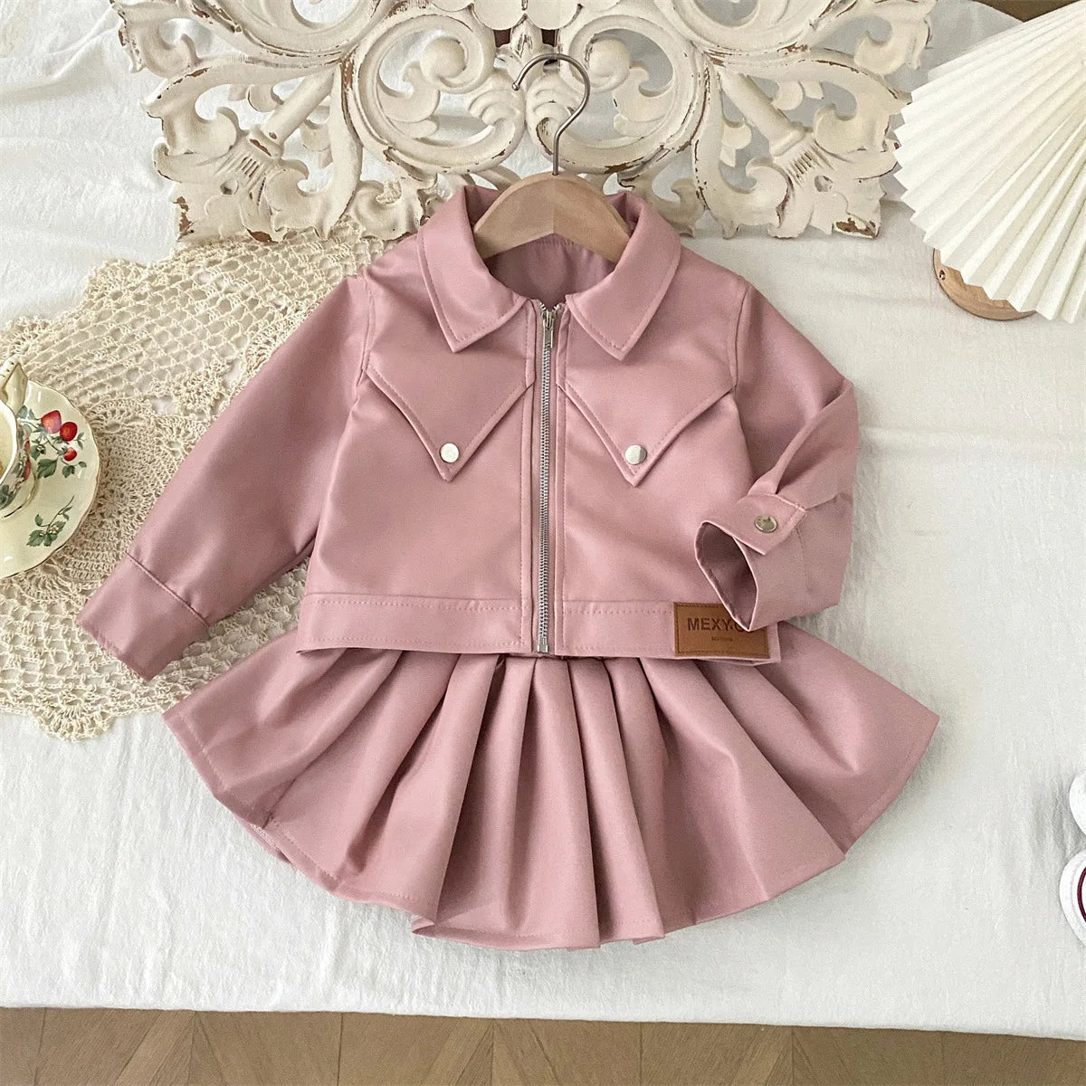 Conjunto de ropa infantil 2025, otoño, nueva y genial chaqueta de cuero sintético para niñas con falda corta, conjunto de dos piezas a la moda.
