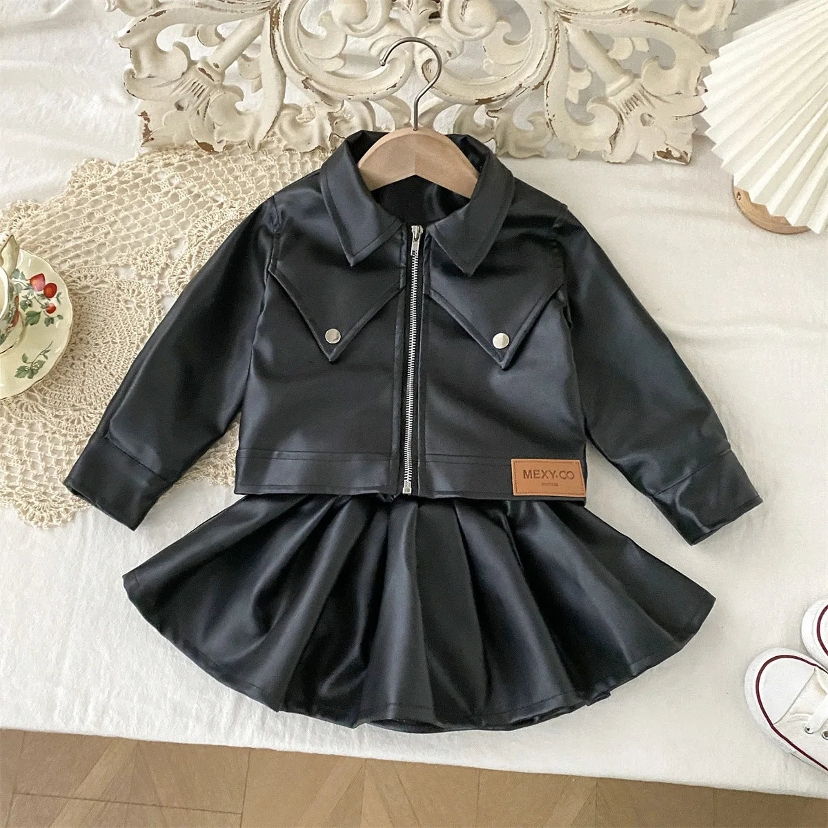 Conjunto de ropa infantil 2025, otoño, nueva y genial chaqueta de cuero sintético para niñas con falda corta, conjunto de dos piezas a la moda.