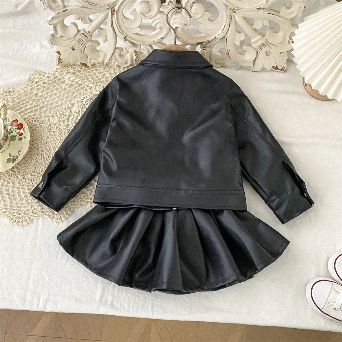 Conjunto de ropa infantil 2025, otoño, nueva y genial chaqueta de cuero sintético para niñas con falda corta, conjunto de dos piezas a la moda.