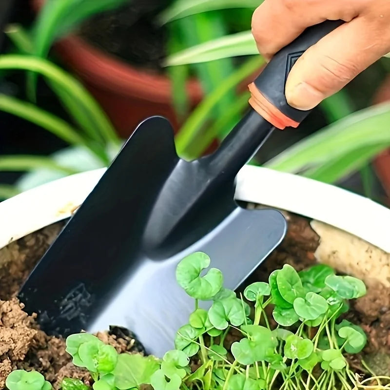 Un juego de cuatro herramientas de jardinería para exteriores que incluye una pala pequeña para plantar flores, un rastrillo de cinco puntas y un rastrillo de dos cabezas.