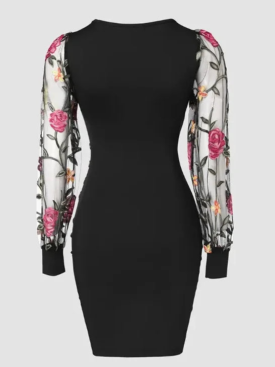 Elegante vestido midi ajustado con bordado floral, mangas de malla transparente y escote en V. Detalle de botones con estilo. Largo hasta la rodilla.